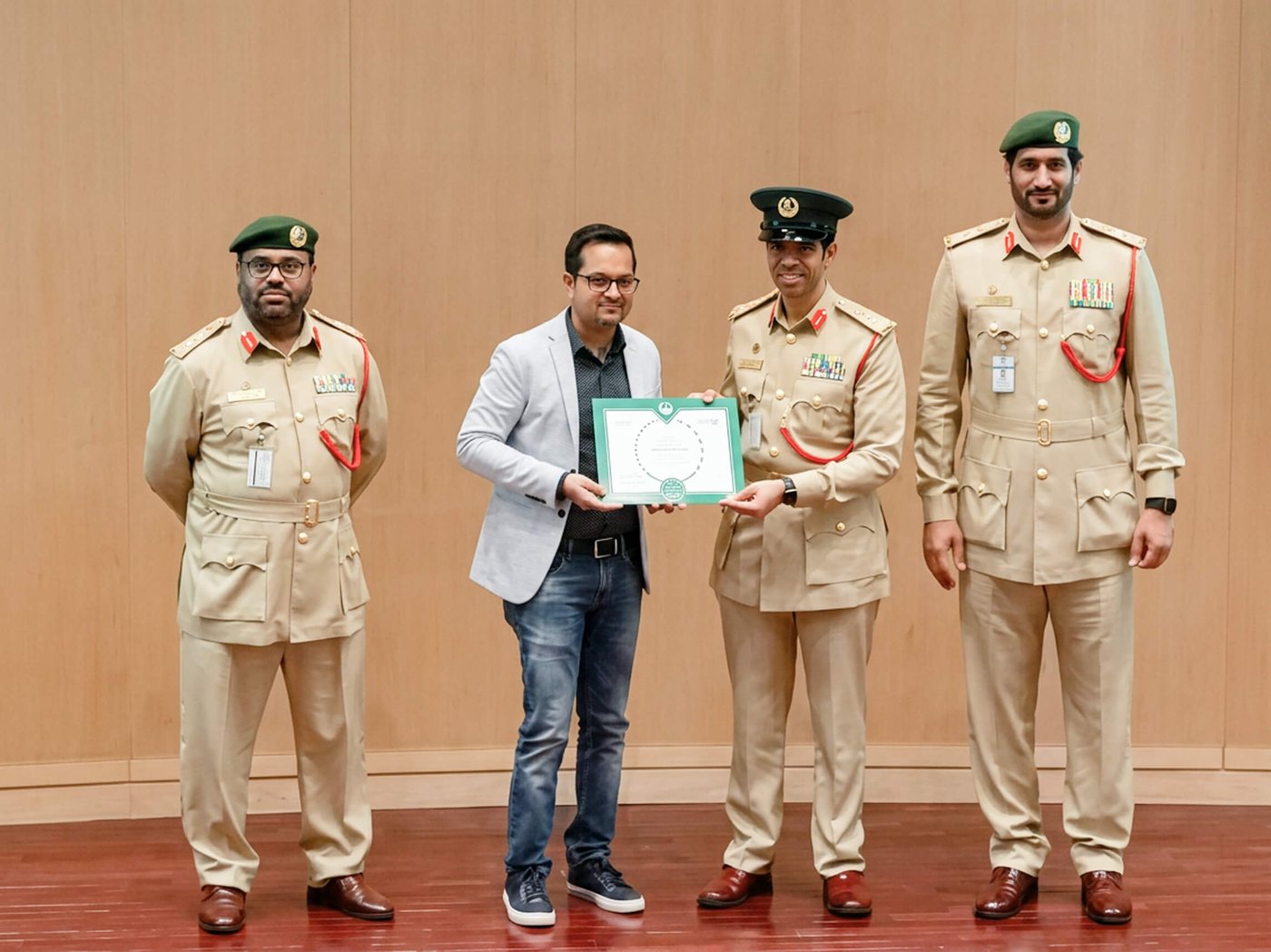 Ramesh receiving a Certificate of Appreciation from Dubai Police officers on stage